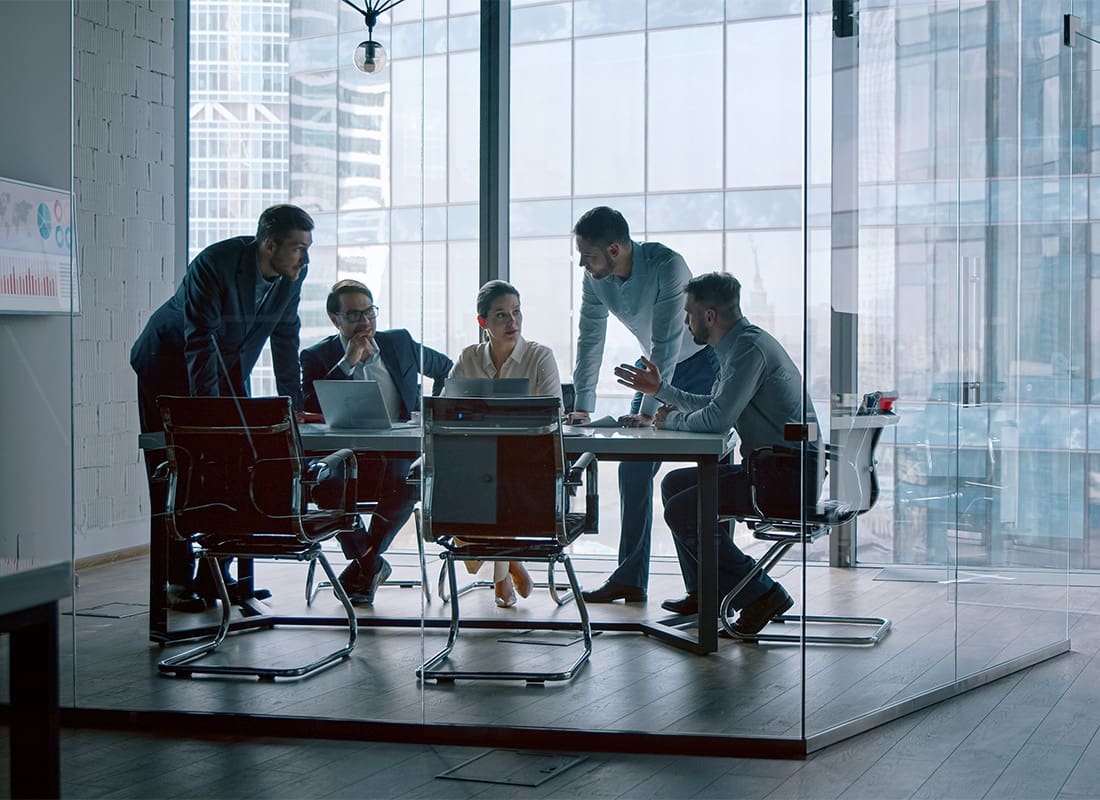 Business Insurance - View of a Small Group of Employees Sitting in a Modern Glass Conference Room in a Corporate Office